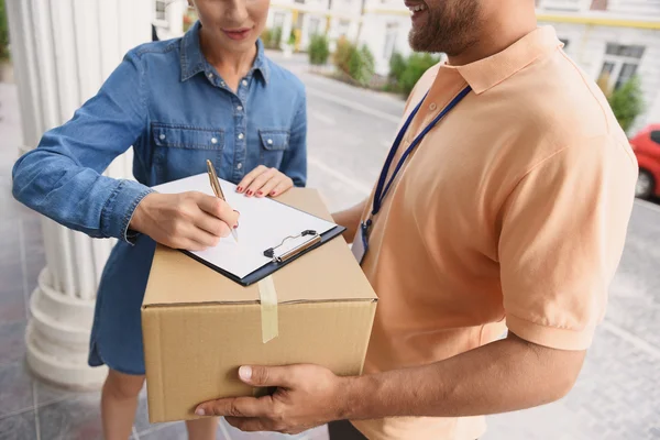 Courier making delivery to beautiful woman — Stock Photo, Image