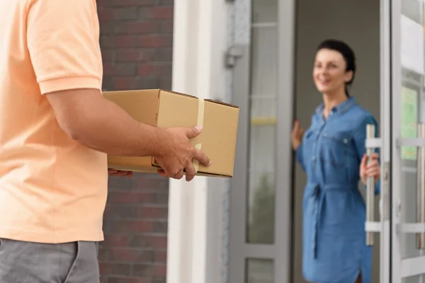 Courier making delivery to beautiful woman — Stock Photo, Image