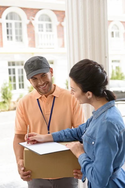Courier making delivery to beautiful woman — Stock Photo, Image