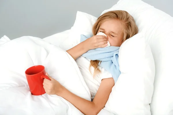 Sick girl holding hot tea in bed — Stock Photo, Image