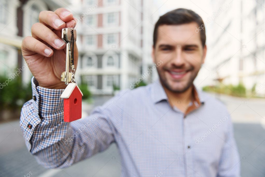 Smiling man holding up keys