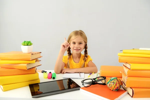 Criança inteligente sentada na mesa com livros — Fotografia de Stock