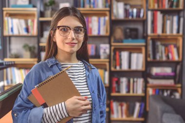 Kampüs kitaplığında duran genç kadın