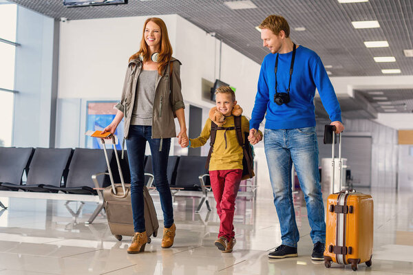 Счастливая семья с чемоданами в аэропорту
