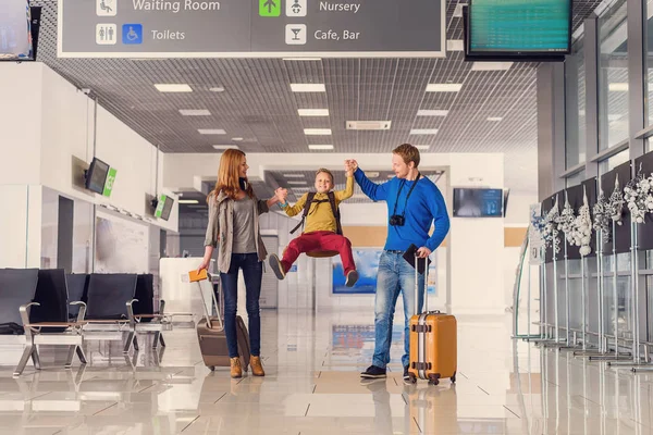 Счастливая семья с чемоданами в аэропорту — стоковое фото