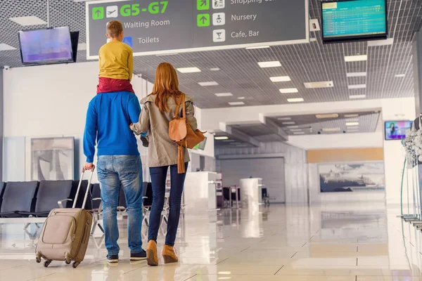 Счастливая семья с чемоданом в аэропорту — стоковое фото