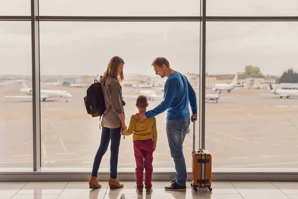 Familie kijkt uit raam op luchthaven — Stockfoto