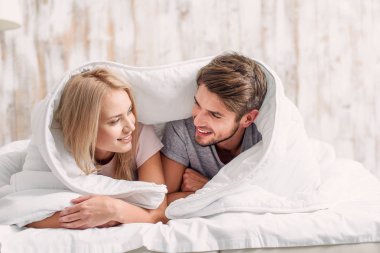 Neşeli aşıklar yatak yorgan altında rahatlatıcı