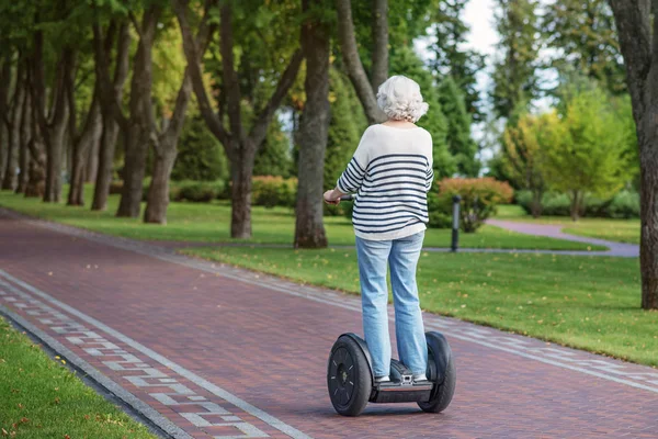 Old lady riding modern transport — Stock Photo, Image