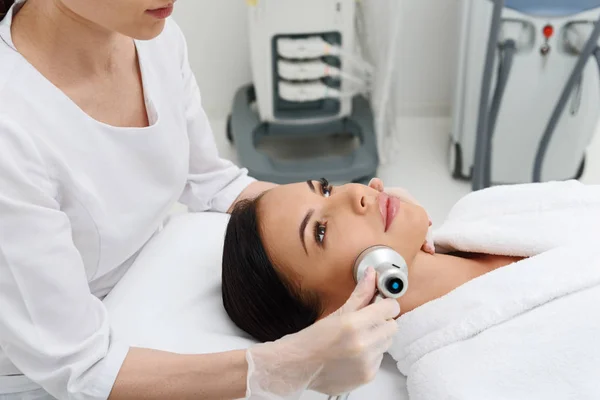 Calm young woman receiving cavitation skincare treatment — Stock Photo, Image