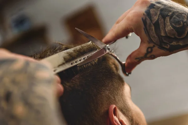 Ножницы и расческа в руках парикмахера — стоковое фото