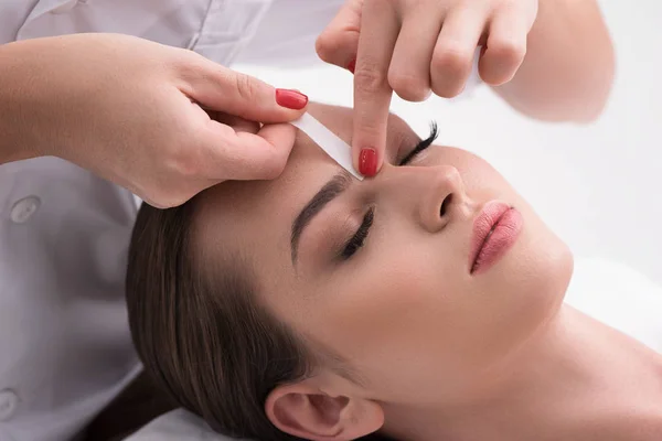 Young woman tweezing her eyebrows in beauty saloon — Stock Photo, Image