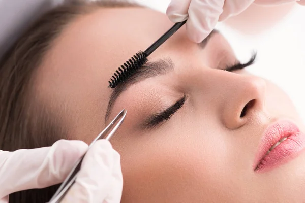 Young woman tweezing her eyebrows in beauty saloon — Stock Photo, Image