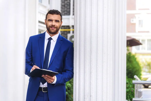 Tipo en el traje de pie junto a la columna del edificio — Foto de Stock