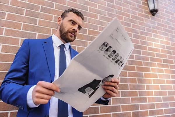 Hombre de negocios buscando algo en un periódico —  Fotos de Stock