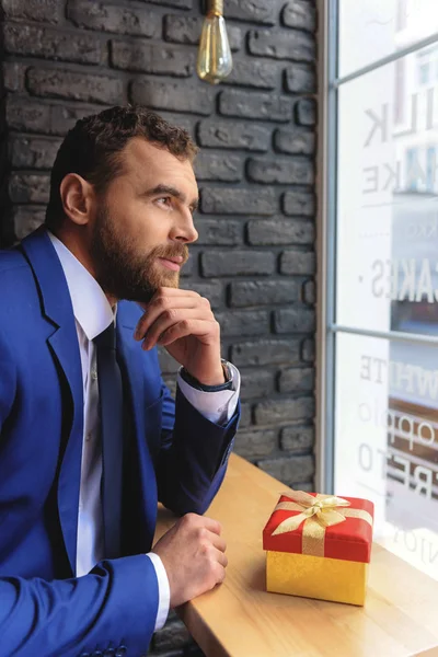 Hombre de negocios elegante con un regalo en el interior —  Fotos de Stock