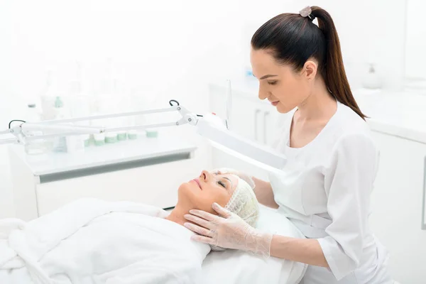 Skickliga cosmetician förbereda patienten för förfarandet — Stockfoto