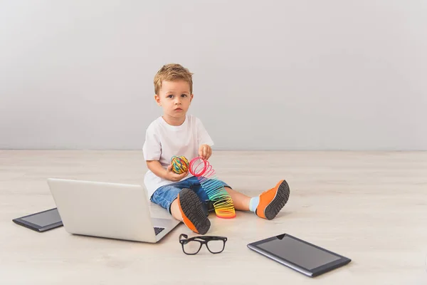 Menino sentado com aparelhos digitais em estúdio — Fotografia de Stock