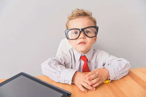 Niño sentado en la mesa en el estudio — Foto de Stock