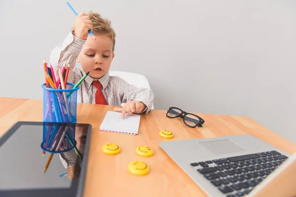 Menino sentado à mesa no estúdio — Fotografia de Stock