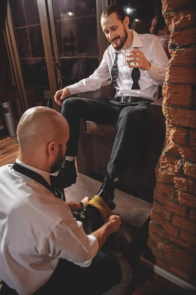 Guy dricka dryck och titta på shoeshiner — Stockfoto