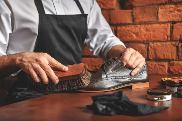 Artigiano in grembiule prendersi cura di stivali eleganti — Foto Stock