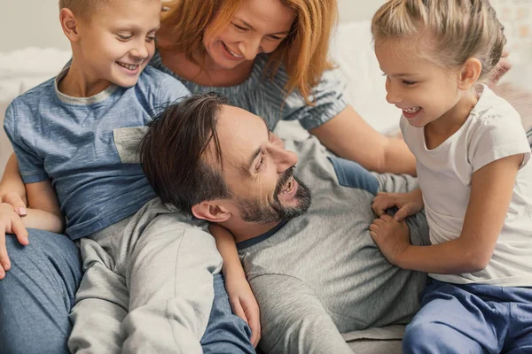 Liggend op bed thuis en gelukkige familie — Stockfoto