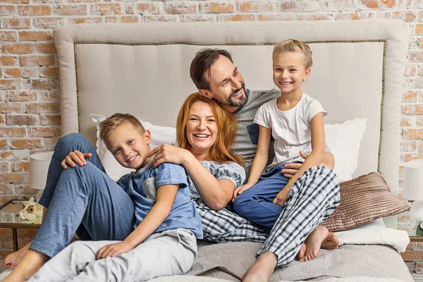 Liggend op bed thuis en gelukkige familie — Stockfoto
