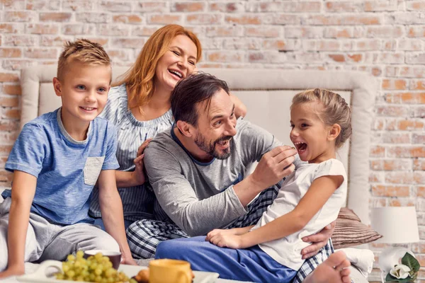 Familia feliz acostada en la cama en casa — Foto de Stock