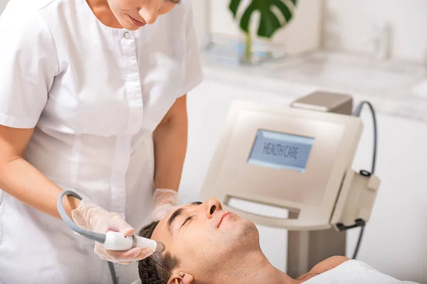 Paciente masculino mayor disfrutando de masaje facial por ultrasonido — Foto de Stock