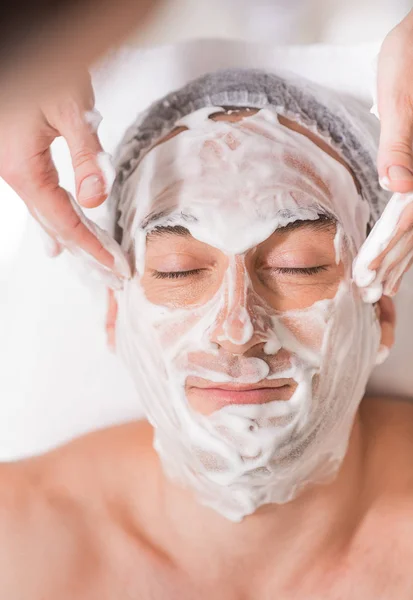 Cosmetologist doing facial massage with foam — Stock Photo, Image