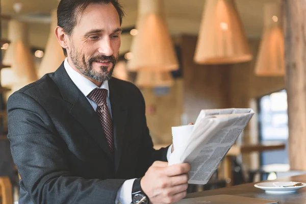 Joyful man resting with paper and hot beverage — Stock Photo, Image