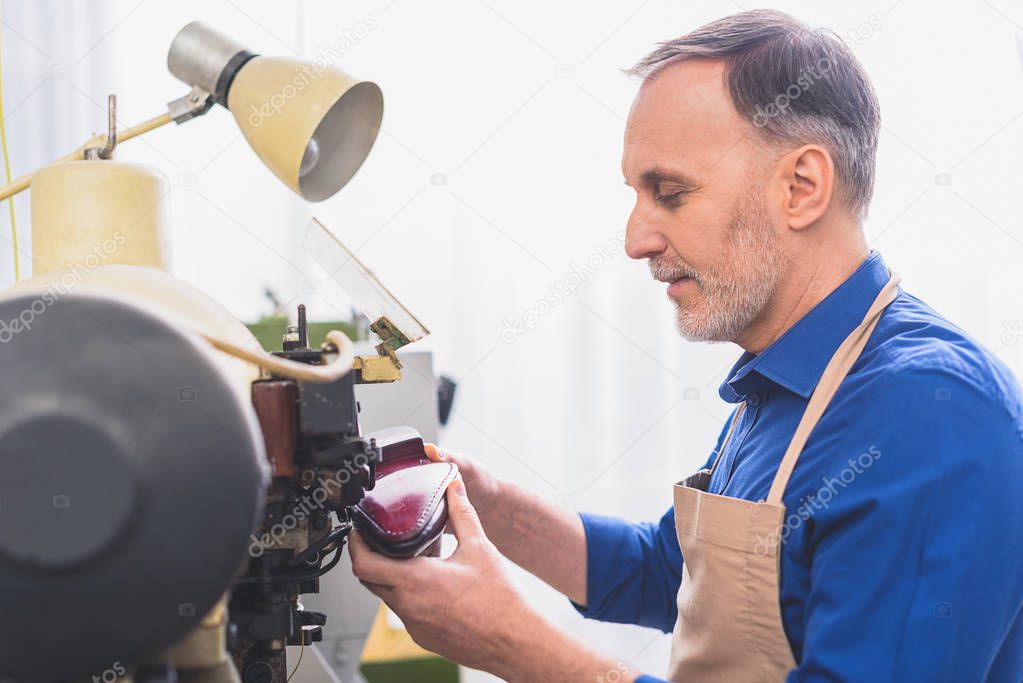 old looking worker sewing a boot