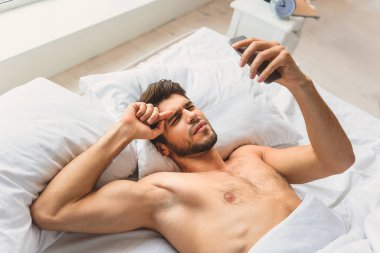 Şaşkın adam cep telefonuyla uykudan sonra