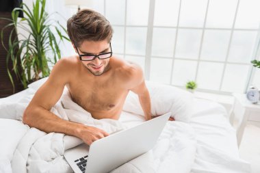 Neşeli adam yatak odasında bilgisayar ile eğlenceli