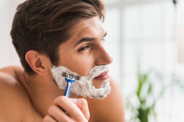 Serious guy shaving his beard clipart