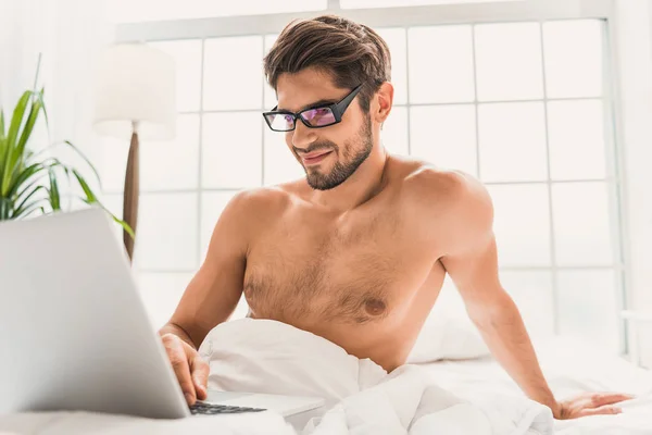 Tipo inteligente usando la computadora en el dormitorio — Foto de Stock