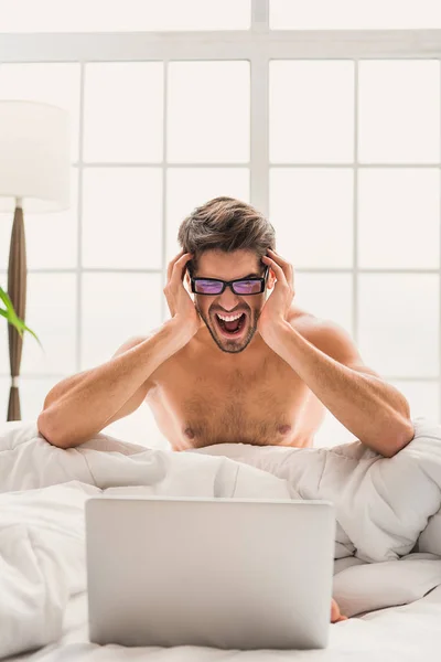 Безумный парень кричит на компьютер в спальне — стоковое фото