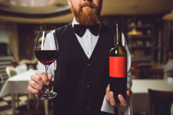 Homem mostrando garrafa e copo de vinho tinto — Fotografia de Stock