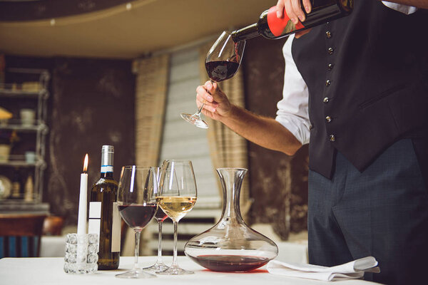 Waiter pouring scarlet wine into glass