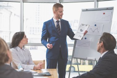 Takım elbiseli adam gülümseyerek konuşuyor