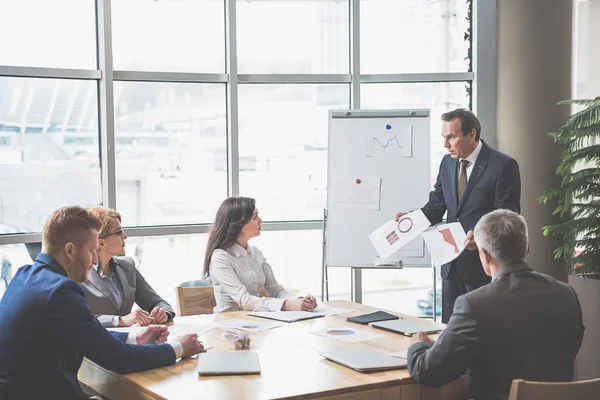 Grupo de personas sentadas alrededor de la mesa — Foto de Stock