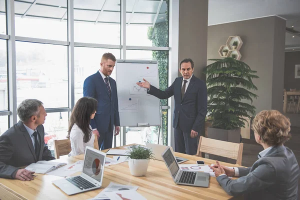 Grupo de personas sentadas alrededor de la mesa — Foto de Stock