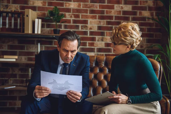 Serious middle aged man holding sheet of paper — Stock Photo, Image