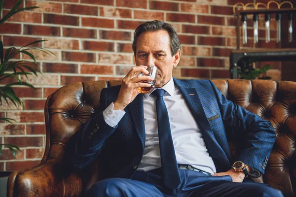 Gondolkodó idősebb ember iszik borostyán ital — Stock Fotó