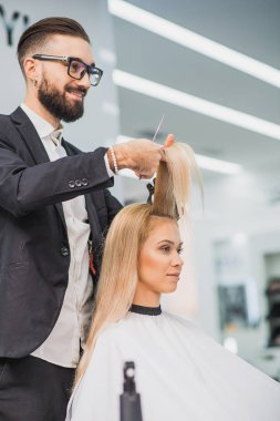 Gülümseyen erkek stilist bir kadın hizmet vermektedir