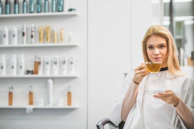 Gülümseyen genç kadın çay içiyor