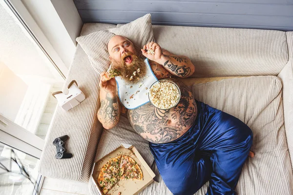 Fat guy eating junk food with enjoyment — Stock Photo, Image