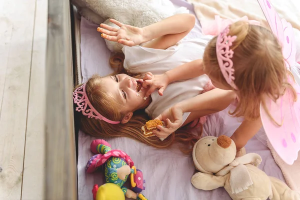 Niños felices jugando con comida dulce en el dormitorio — Foto de Stock