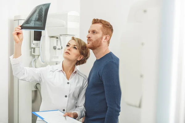 Серйозна жінка-лікар в кабінеті з рентгенівським апаратом — стокове фото